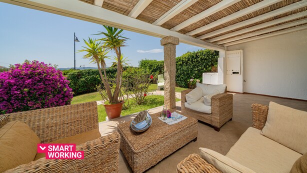 Un patio al aire libre con mobiliario de mimbre, una planta en maceta y vistas del paisaje.