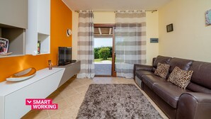 Una sala de estar moderna con un sofá de cuero marrón, una mesita consola blanca y una alfombra de pelo alto gris.