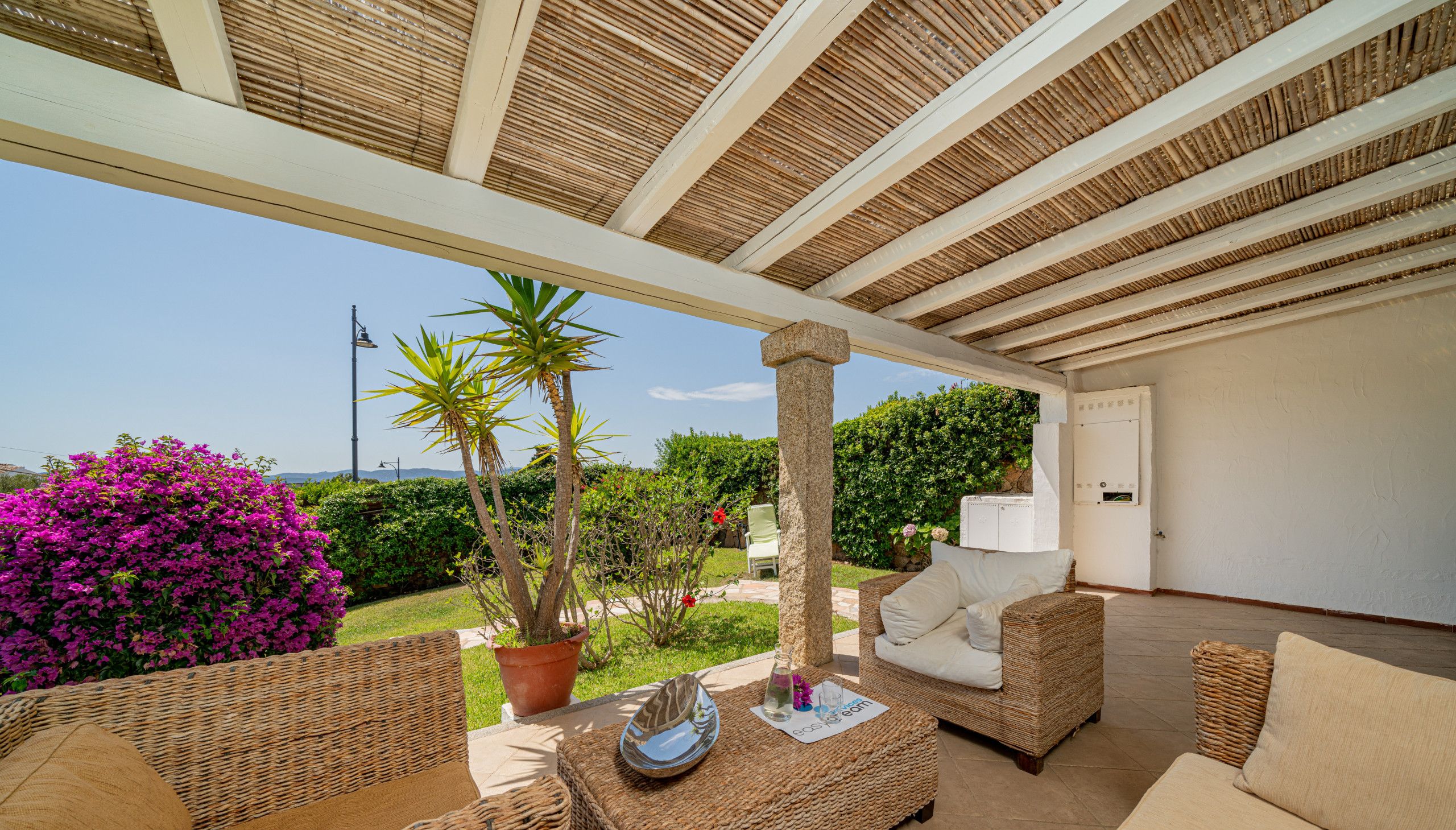 An outdoor patio area with wicker furniture, a potted plant, and a view of the landscape.
