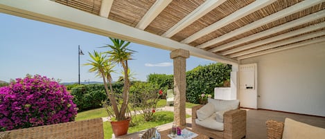 Un espace extérieur aménagé en terrasse, avec des meubles en osier, une plante en pot et une vue sur le paysage.