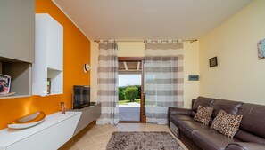 Una sala de estar moderna con un sofá de cuero marrón, una mesita consola blanca y una alfombra de pelo alto gris.