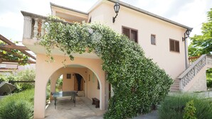 A building with an arched entrance, a staircase, and a table with chairs outside.