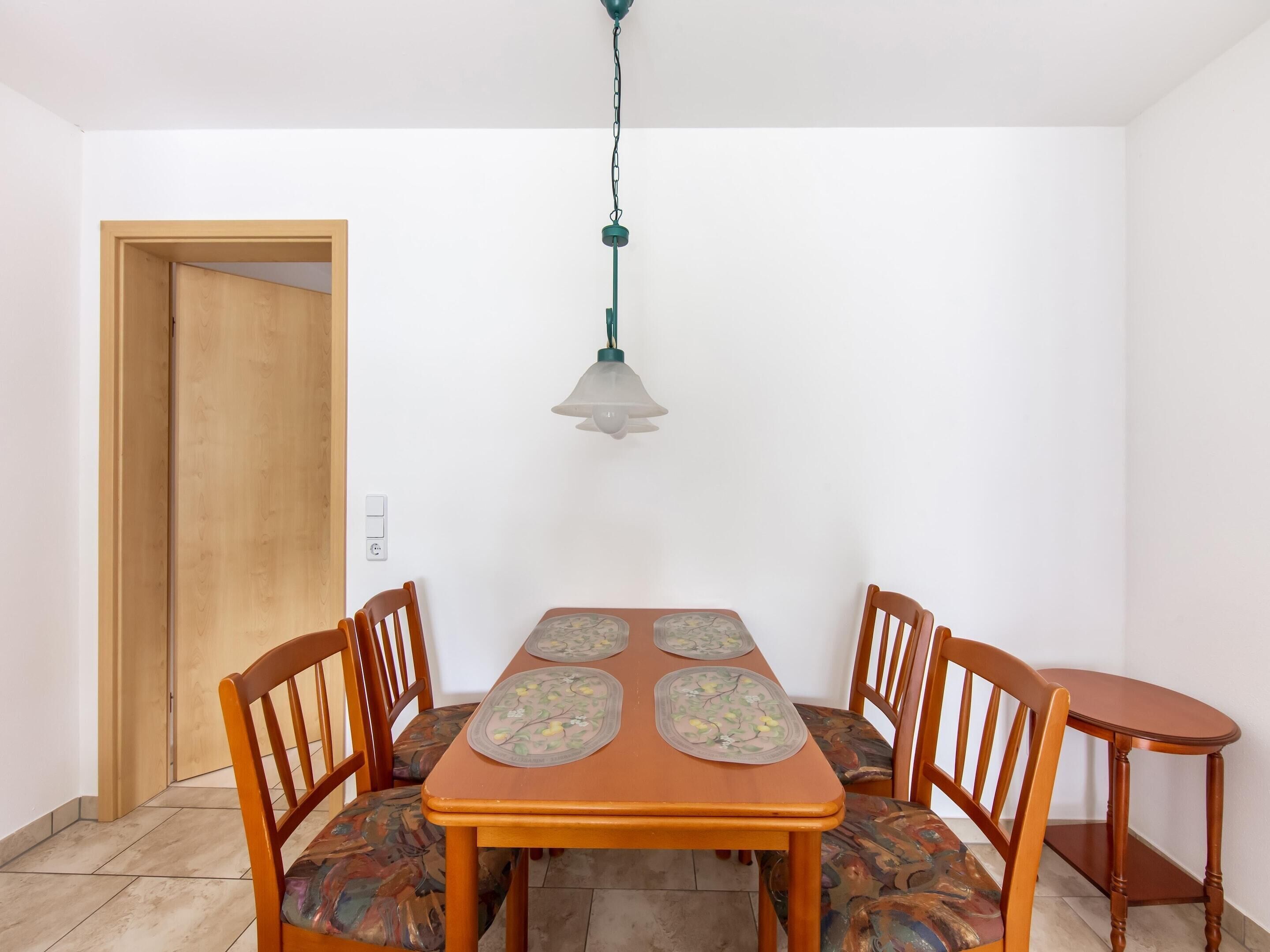 Un coin repas avec une table en bois, quatre chaises et un luminaire suspendu.