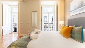 A hotel room with a large bed, a view of the outside balcony, and a painting on the wall. - Modern Chiado by Homing (Lisbon)