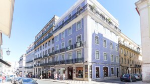 A building with a blue and white facade, multiple balconies, and a ground-level shop. - Modern Chiado by Homing (Lisbon)