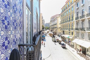 Una vista di strada con edifici caratterizzati da piastrelle a motivi blu e bianchi, strada acciottolata e zone con tavoli all'aperto.