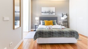 A modern hotel room with a large bed, bedside tables, a mirror, and a painting on the wall. - Modern Chiado by Homing (Lisbon)