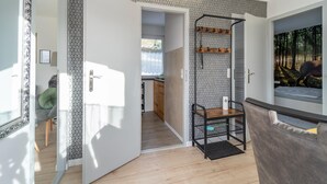 A hallway with patterned walls, a wooden floor, and a door leading to a room with a bed and a window. - Ferienhaus in Suhl in der Nahe des Rennsteigs (Suhl)