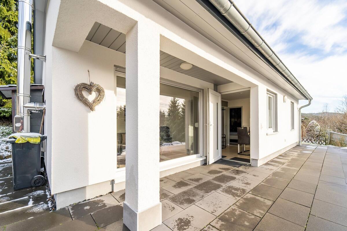 A modern house with a covered patio, large windows, and a heart-shaped decoration on the wall.