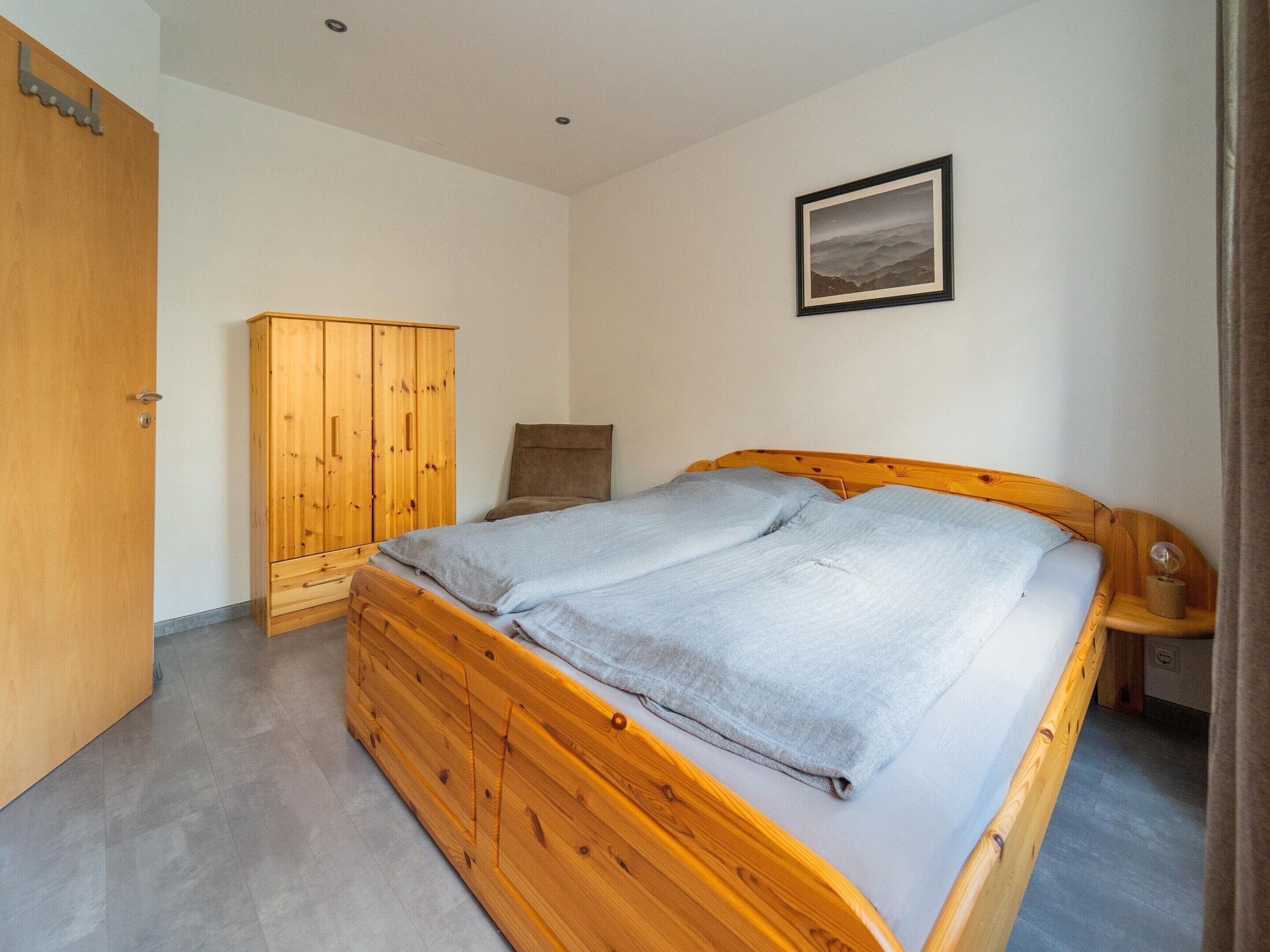 A bedroom with a wooden bed, a wardrobe, and a framed picture on the wall.