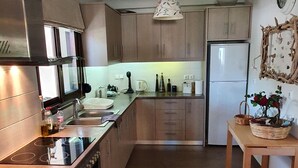 A modern kitchen with stainless steel appliances, wooden cabinets, and a central island. - Apartment in Loutra Elenis With Garden (Corinth)