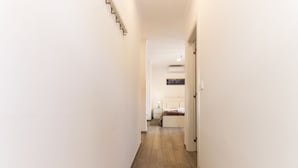 A narrow hallway with wooden flooring leading to a bedroom with a bed and a nightstand. - Downtown Palma Suites by Homing (Lisbon)