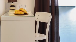 A white desk with a lamp, a plate with croissants, and a glass of orange juice. - Downtown Palma Suites by Homing (Lisbon)