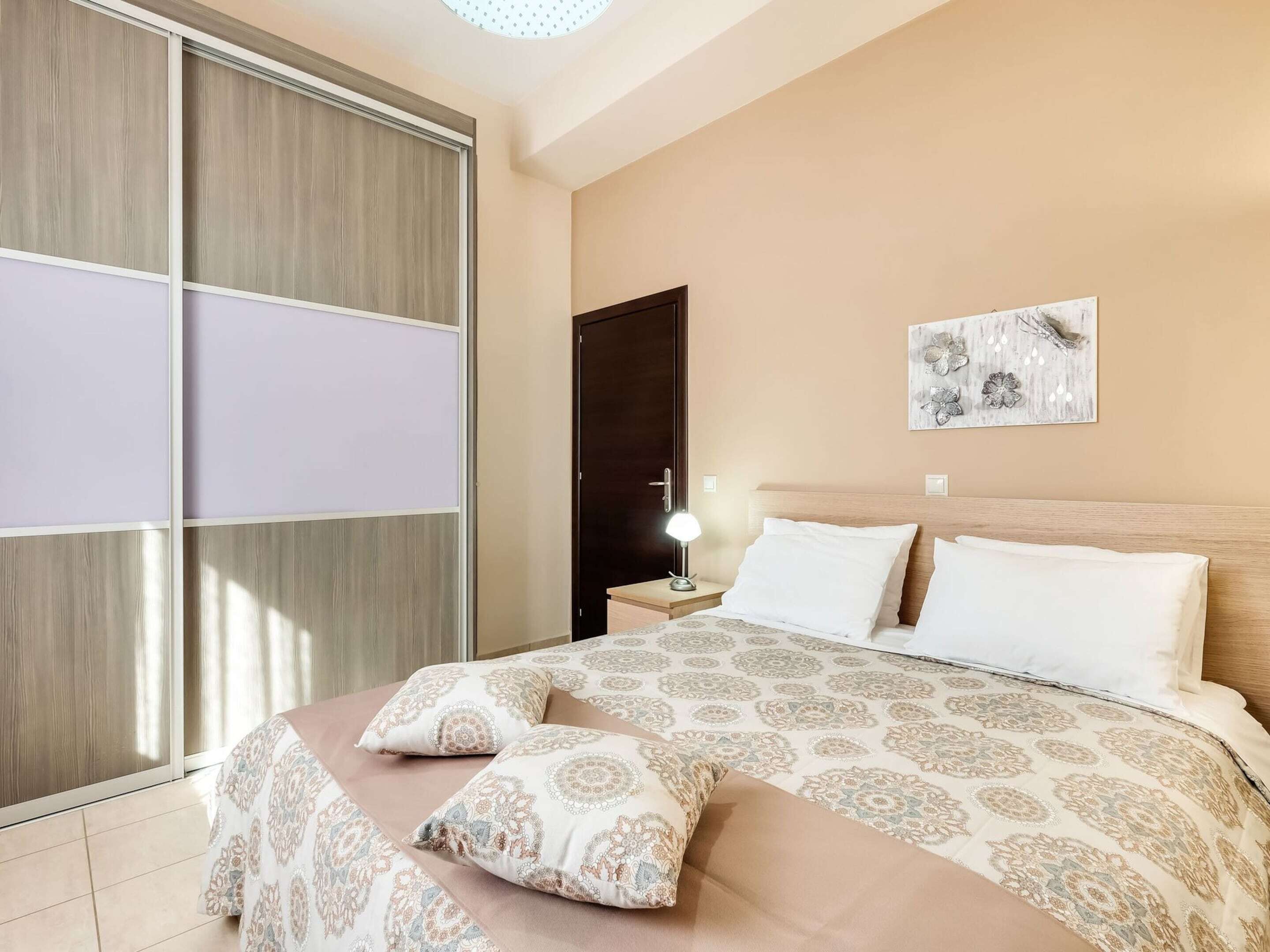 A bedroom with a bed, nightstand, and a wall-mounted lamp.
