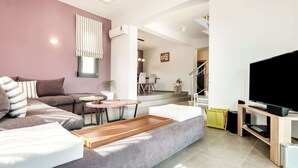A modern living room with a sofa, a coffee table, a TV, and a staircase leading to an upper floor. - Villa in Crete With Stunning Rural Views (Rethymno)
