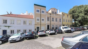 Un estacionamiento con varios coches aparcados frente a edificios de arquitectura europea clásica.