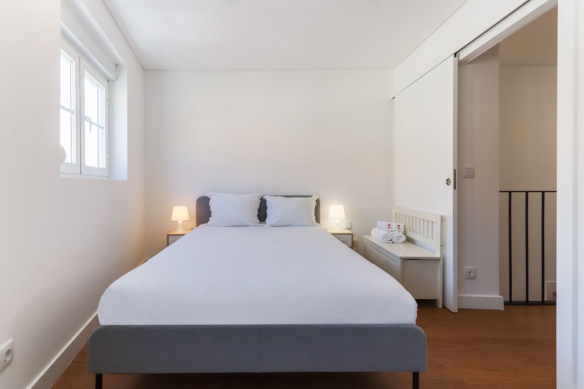 A neatly arranged bedroom with a bed, bedside tables, and a nightstand.