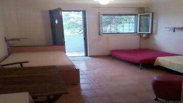 A room with a bed, a bench, a small table, and a window.