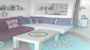 A living room with a sofa, a coffee table, and a ceiling fan. There are shelves with books and decorative items. - Cheerful Holiday Home in Preveza With Garden (Preveza)