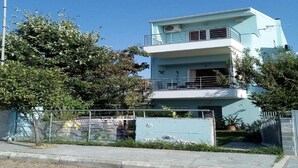 A multi-story residential building with balconies, a fenced yard, and a clear sky. - Cheerful Holiday Home in Preveza With Garden (Preveza)