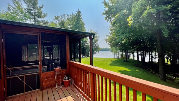 Una terraza de madera con vista a un lago y árboles.