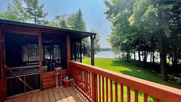 Une terrasse en bois offrant une vue sur un lac et des arbres.