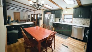 Una cocina compacta con una mesa de comedor de madera, armarios oscuros y un refrigerador empotrado.