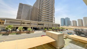 Un moderno edificio de gran altura con varios balcones, una zona de estacionamiento techada y un cielo despejado.