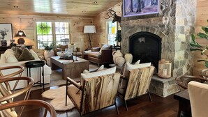 A cozy cabin interior with a stone fireplace, wooden ceiling, and a comfortable seating area. - NEW ADIRONDACK LUXURY CABIN WITH YEAR-ROUND HEATED PLUNGE POOL (Old Forge)