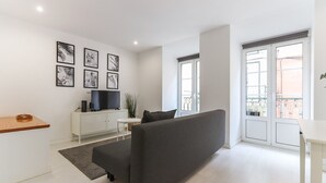 A modern living room with a grey sofa, a white TV stand, and a small round table. - Graça Elegant by Homing (Lisbon)