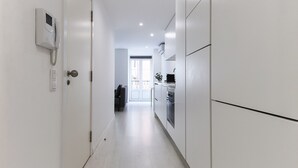 A narrow hallway with white walls and a door leading to a kitchen area. - Graça Elegant by Homing (Lisbon)