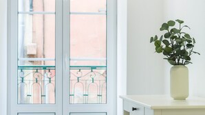 A room with a white door, a balcony with a metal railing, and a white table with a plant in a vase. - Graça Elegant by Homing (Lisbon)