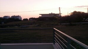 A balcony with a metal railing overlooking a grassy area with buildings in the background. - Holiday Home in Greece Near the Beach (Preveza)