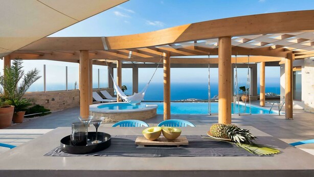 An outdoor pool area with a view of the sea, wooden pergolas, lounge chairs, and a table with fruit and a drink tray. - Luxury Villa With Heated Pool 700m to the Beach (Malevizi)