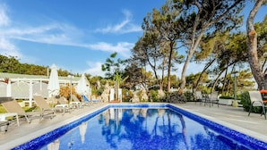 A clear blue swimming pool with lounge chairs and umbrellas, surrounded by trees and a white fence. - Beautiful Holiday Home With Private Pool (Rhodes)