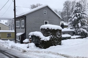 Enjoy a peaceful winter retreat in this cozy home with a gabled roof and inviting front porch.