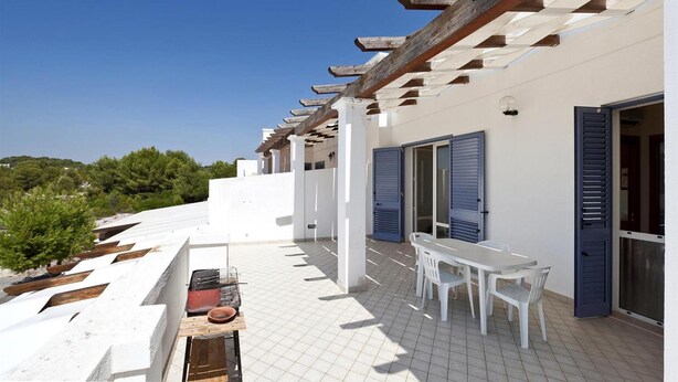 A white building with a tiled patio, a barbecue grill, and a table with chairs. - 199 Casa a 500m dal Mare a S M di Leuca (Castrignano del Capo)
