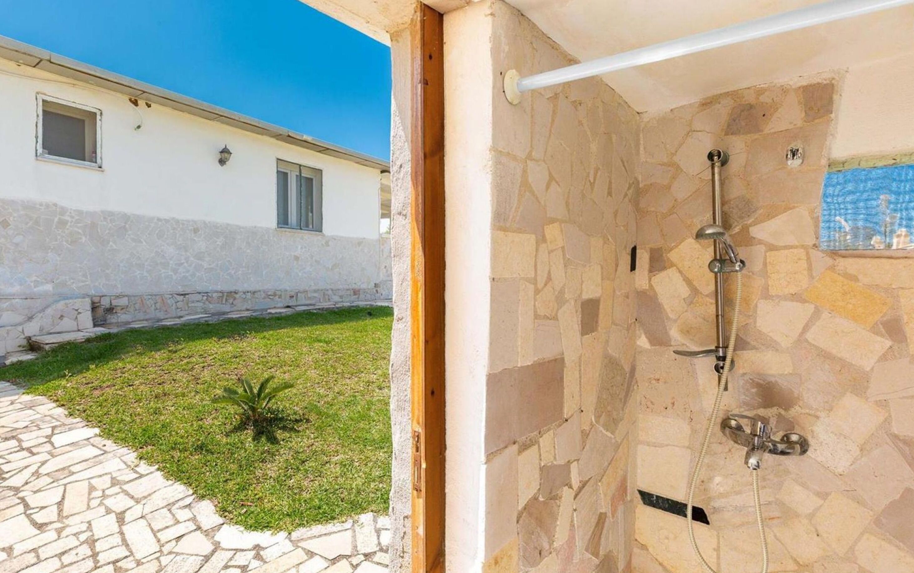 A stone shower with a handheld showerhead and a wall-mounted faucet.