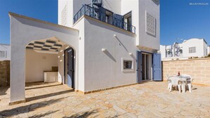 Une villa moderne dotée d’un patio en pierre, d’un espace salon extérieur et d’une entrée couverte.