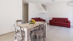 Un espace repas avec une table et des chaises en bois, un canapé rouge et un escalier.