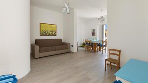 A living room with a sofa, a dining table with chairs, and a painting on the wall. - 1659 Dodger House in Porto Cesareo (Porto Cesareo)
