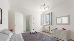A bedroom with a bed, a dresser, a mirror, and a chandelier. - 1659 Dodger House in Porto Cesareo (Porto Cesareo)