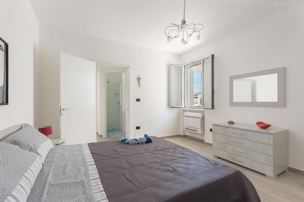 Un dormitorio con cama, cómoda, espejo y candelabro.
