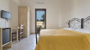 Een slaapkamer met een bed, een bureau met stoel, een televisie en een kledingkast.