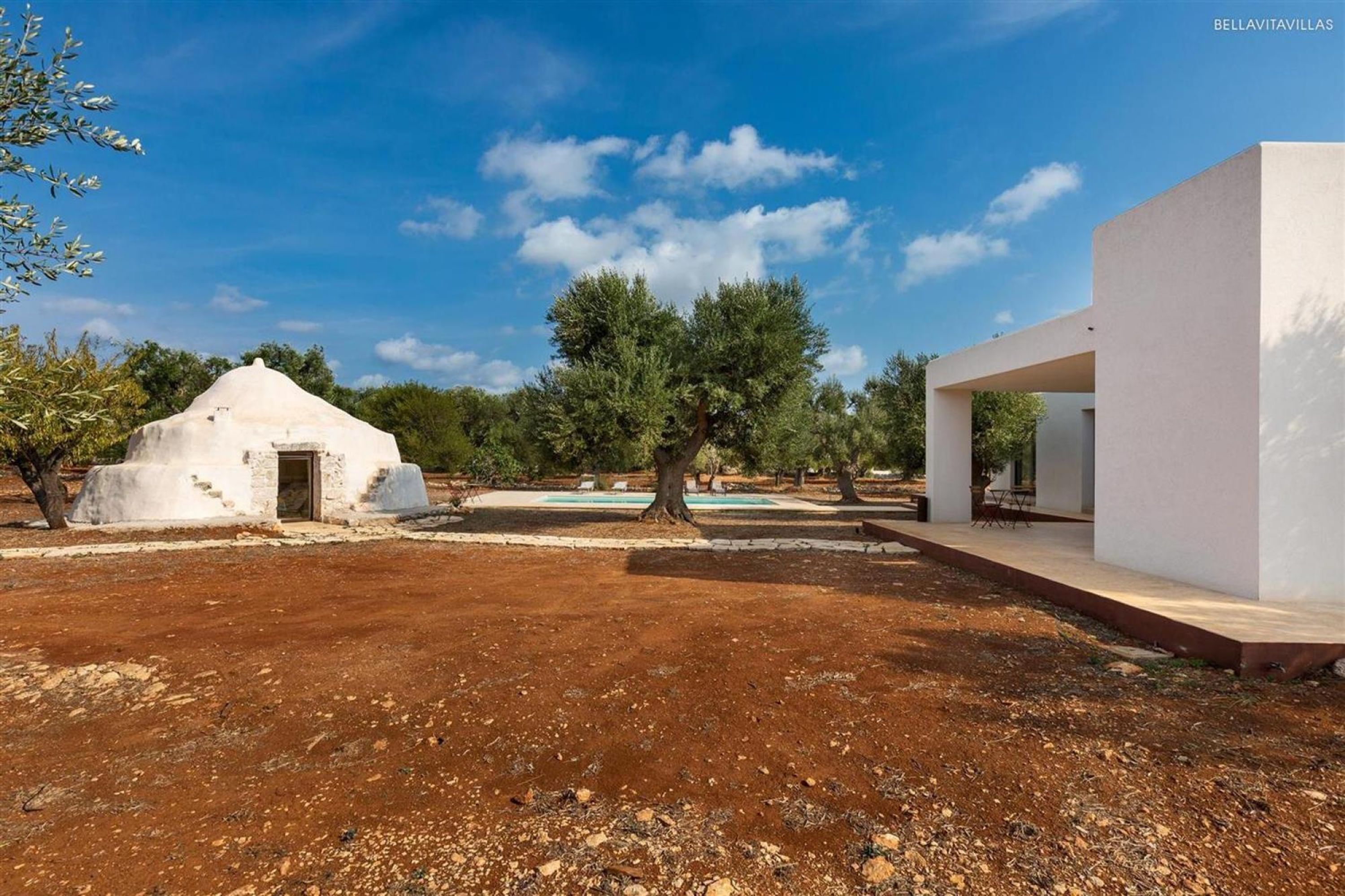 Une villa moderne à l’extérieur blanc, dotée d’un petit jardin et d’une piscine.