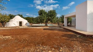 A modern villa with a white exterior, a small garden, and a pool.