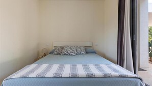 A bedroom with a bed, a nightstand, a lamp, and a view through a window.