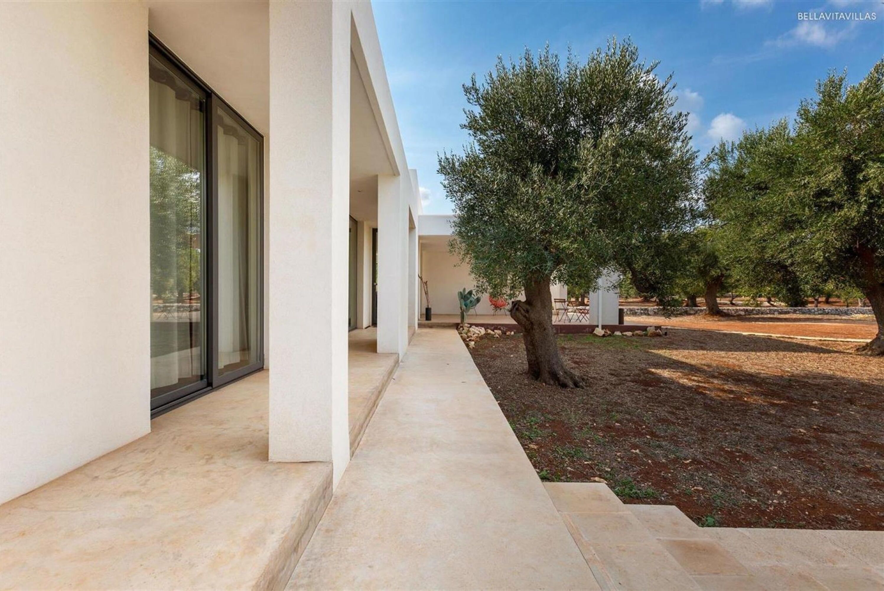 A modern building with a covered outdoor area, a tree, and a clear sky.