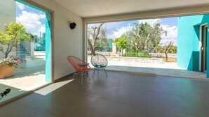 Una habitación amplia con ventanas grandes, una planta en maceta y dos sillas.