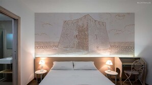 Una habitación de hotel con una cama grande, dos mesitas de noche con lámparas, un escritorio y una silla.